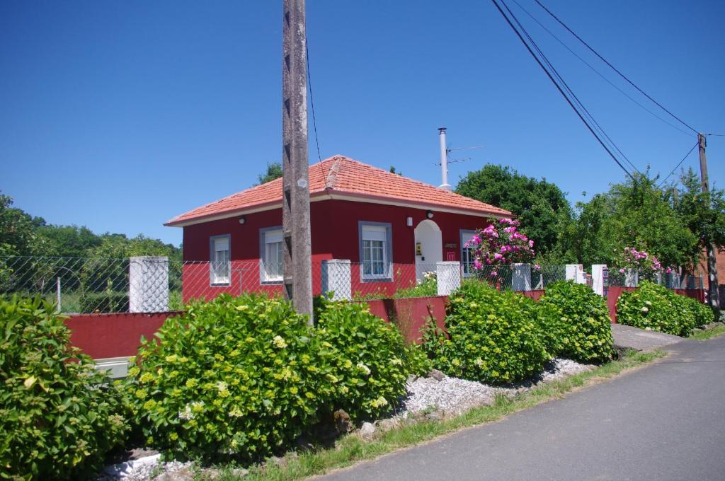 uma casa vermelha com um telhado vermelho e alguns arbustos em CAMBOTE Vivienda turìstica em Lugo