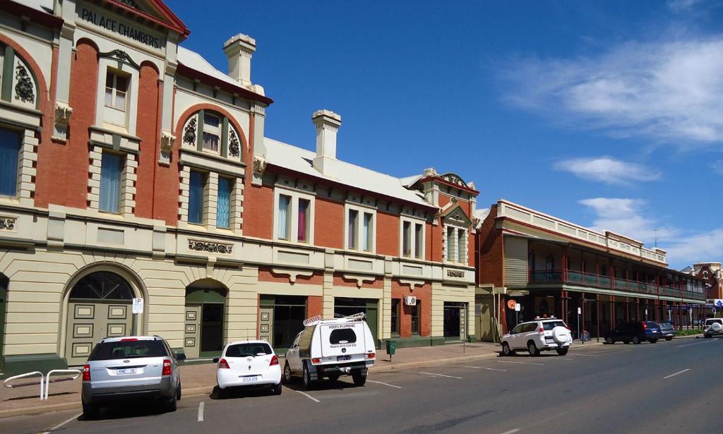 een straat met auto's geparkeerd voor een gebouw bij The Palace Hotel Kalgoorlie in Kalgoorlie