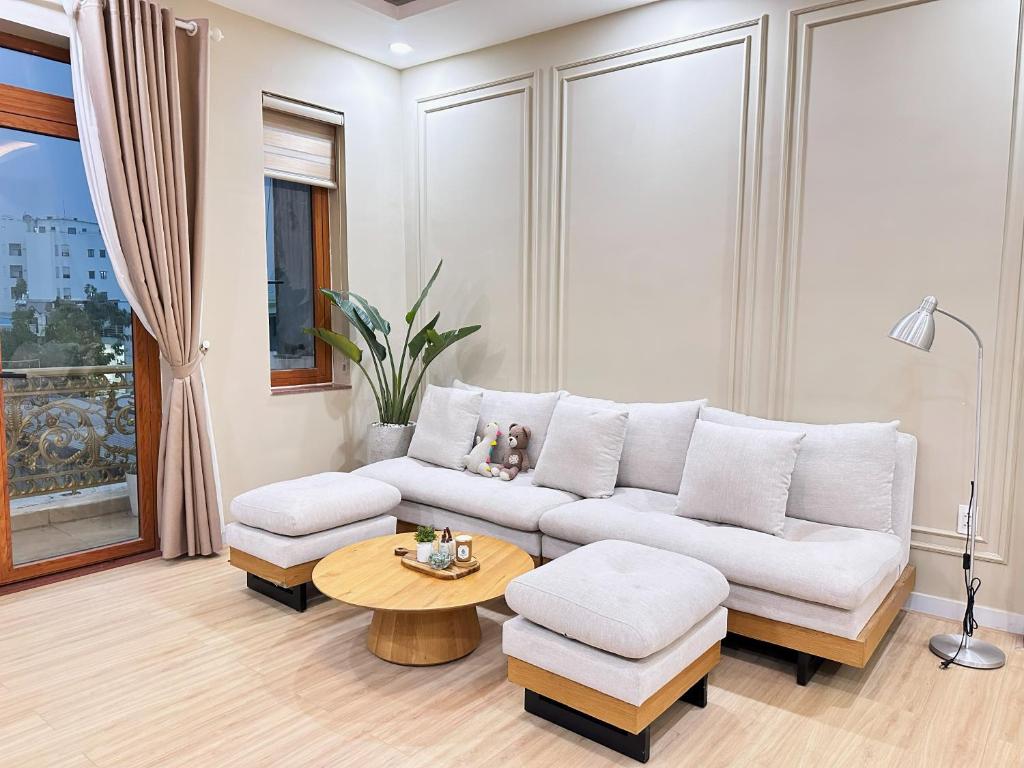 ein Wohnzimmer mit einem weißen Sofa und einem Tisch in der Unterkunft Secret Elm Hotel in Ho-Chi-Minh-Stadt