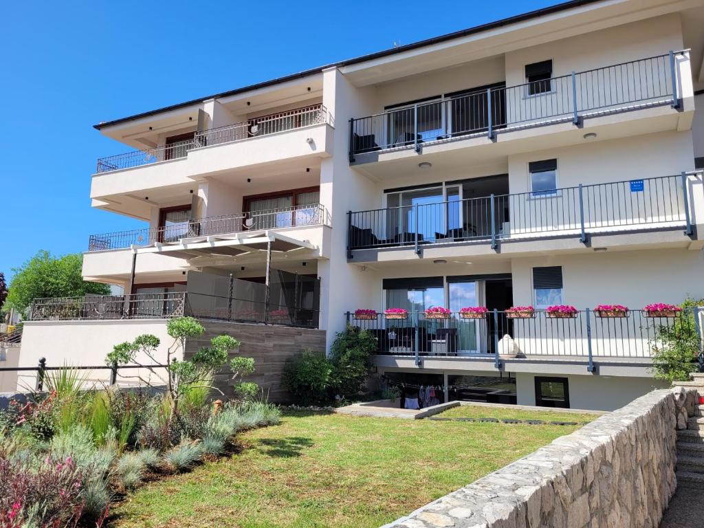 an apartment building with balconies and a yard at Apartments Doris in Malinska
