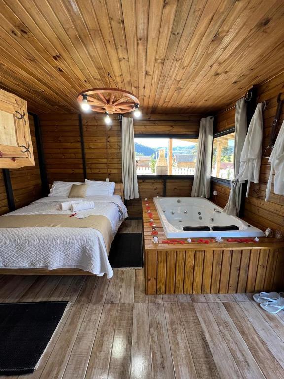 1 dormitorio con 2 camas y bañera. en Chalés Refúgio Ohana, en Urubici
