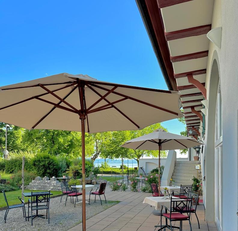 eine Terrasse mit Tischen, Stühlen und einem Sonnenschirm in der Unterkunft SeeHotel Amtshof in Langenargen