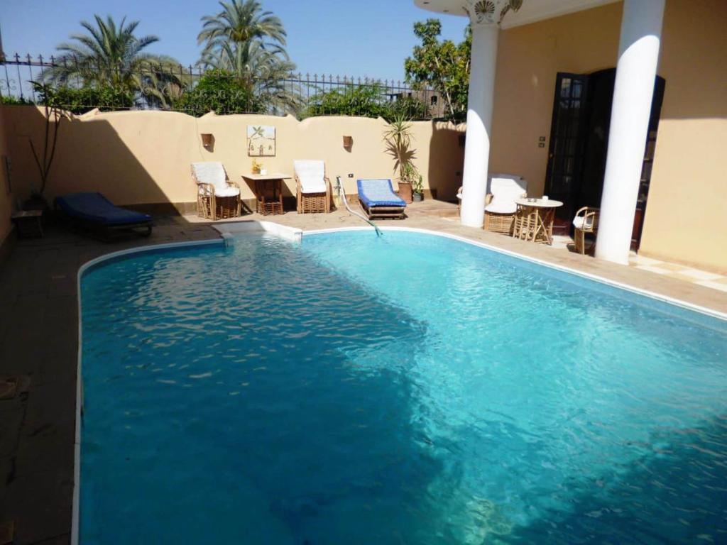 a large blue swimming pool with chairs and a table at Nile Dream Apartments in Luxor