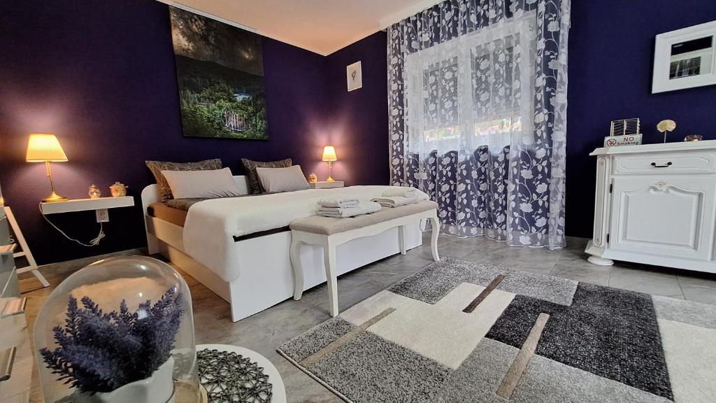 - une chambre avec un lit blanc et des murs violets dans l'établissement Studio apartman Marta, à Korenica