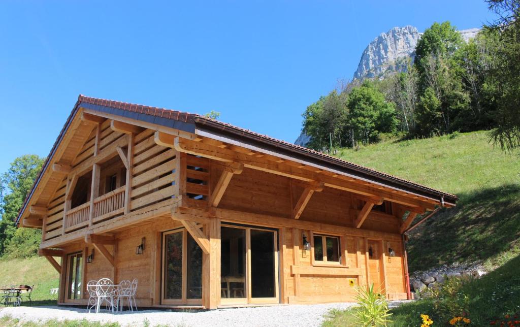 una cabaña de madera con una montaña en el fondo en Demi-Chalet Savoyard, en Le Petit-Bornand-lès-Glières