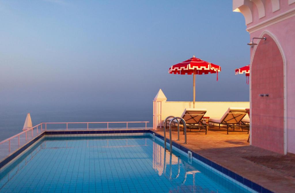 einen Pool mit einem Sonnenschirm, 2 Stühlen, einem Tisch und einem Sonnenschirm in der Unterkunft Il Capri Hotel in Capri
