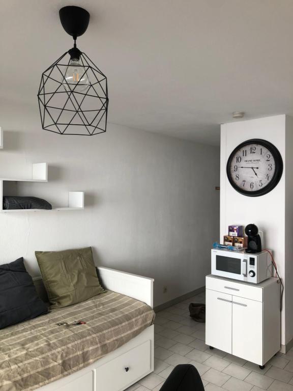 une chambre avec un lit et une horloge au mur dans l'établissement Très beau studio près du centre ville, à Nîmes