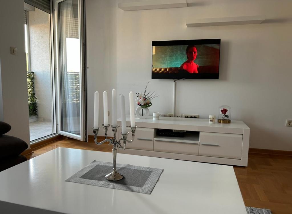 soggiorno con TV a parete e candele di Apartment Shine a Podgorica