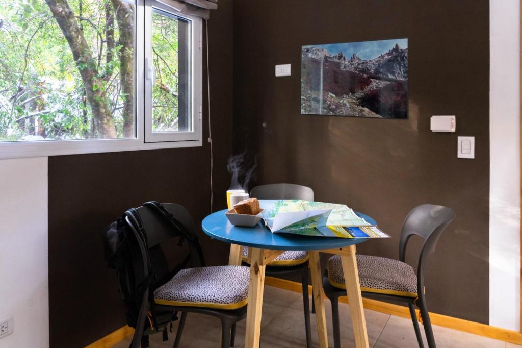 Una mesa y sillas azules en una habitación con ventana. en Casa en el Bosque, en San Carlos de Bariloche