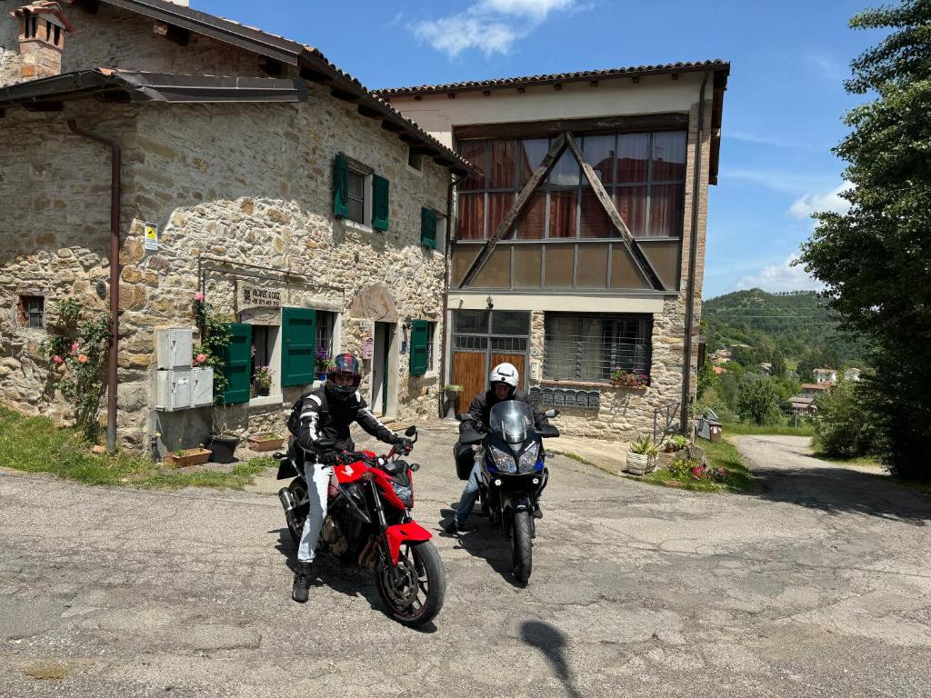 zwei Personen auf Motorrädern, die vor einem Gebäude geparkt sind in der Unterkunft La corte dei celti la fonte 1 in San Benedetto Del Querceto