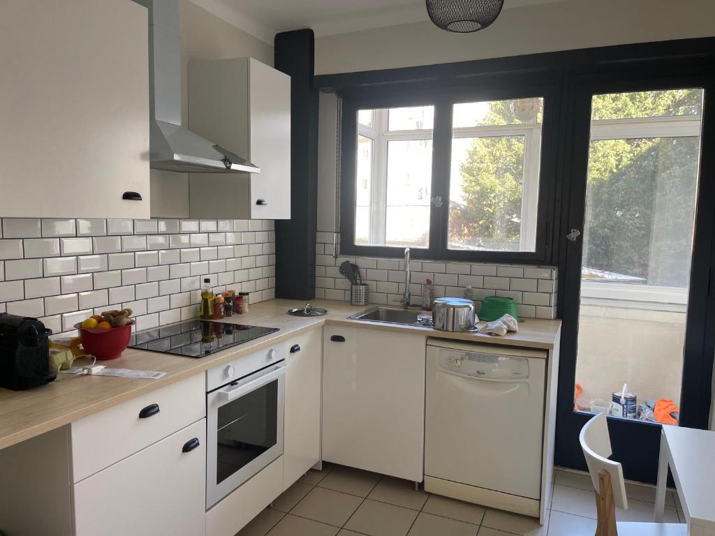 une cuisine avec des armoires blanches, un évier et une fenêtre dans l'établissement Ribeauvillé, à Strasbourg