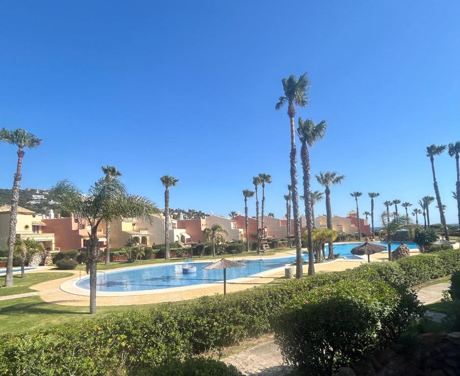 a swimming pool with palm trees in a resort at A pie de playa con vistas al mar in Zahara de los Atunes