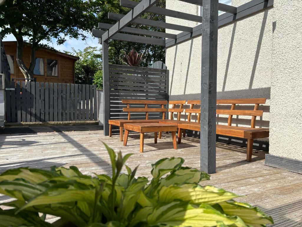 two wooden benches sitting under a pergola at Craster Crew Quarters in Craster