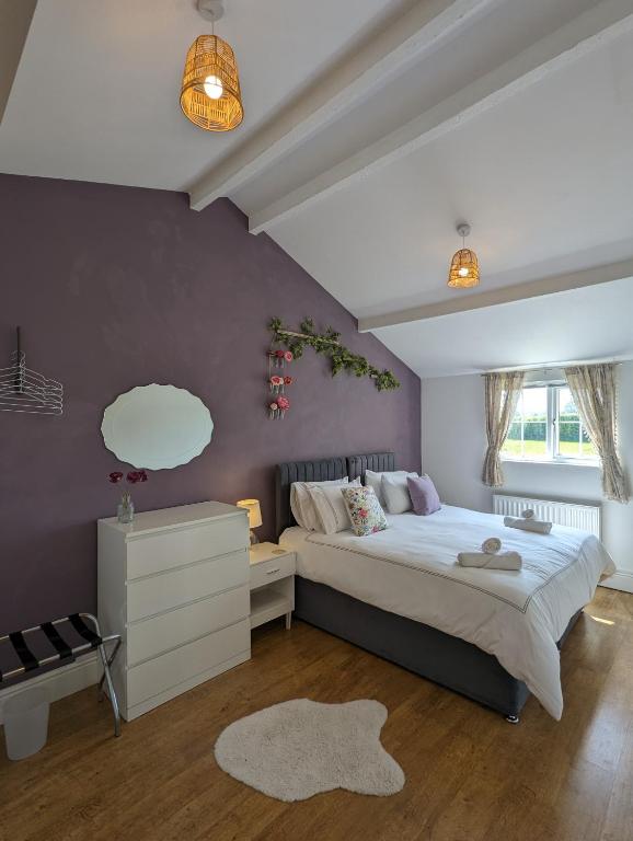 a bedroom with a large bed and a purple wall at The Stables at Wits End, Hartford in Hartford