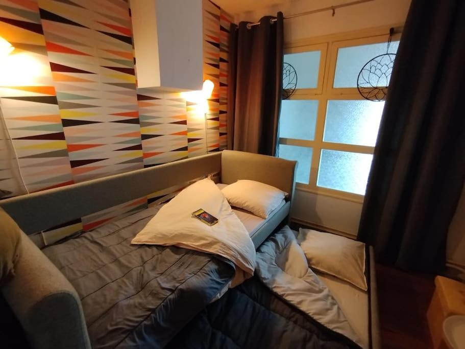 a small bed in a room with a window at Appartement plein centre avec terrasse in Lons-le-Saunier