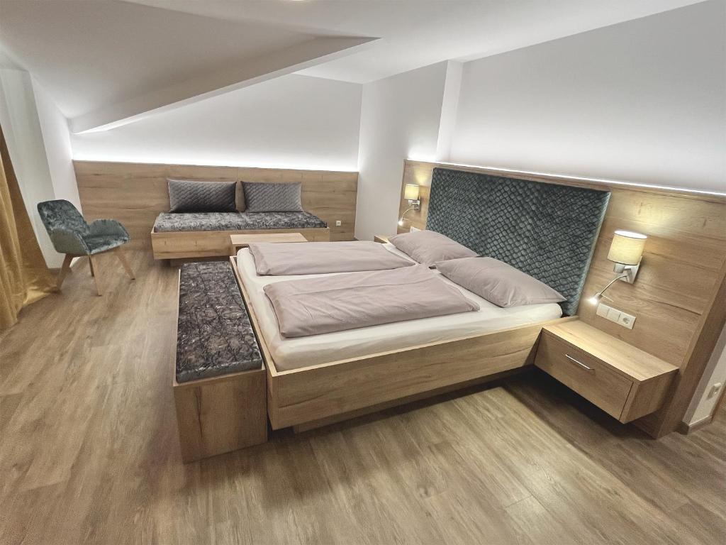 ein Schlafzimmer mit einem großen Bett und einem Stuhl in der Unterkunft Hotel Sonnenheim in Sterzing