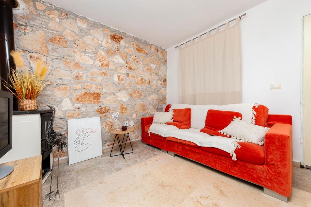 a red couch in a room with a stone wall at Apartman Babich in Rovinj