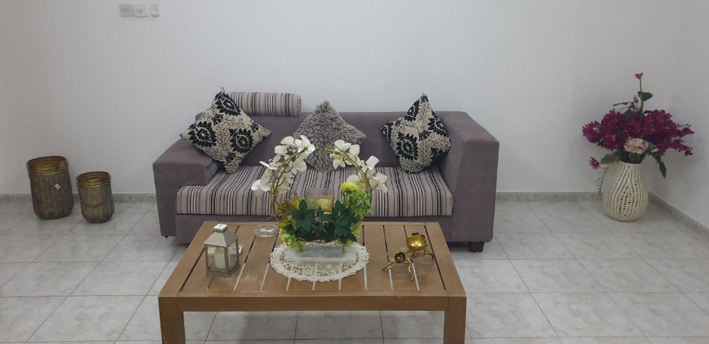 uma sala de estar com um sofá e uma mesa com flores em HOUSE IN AL AIN - 4 em Al Ain