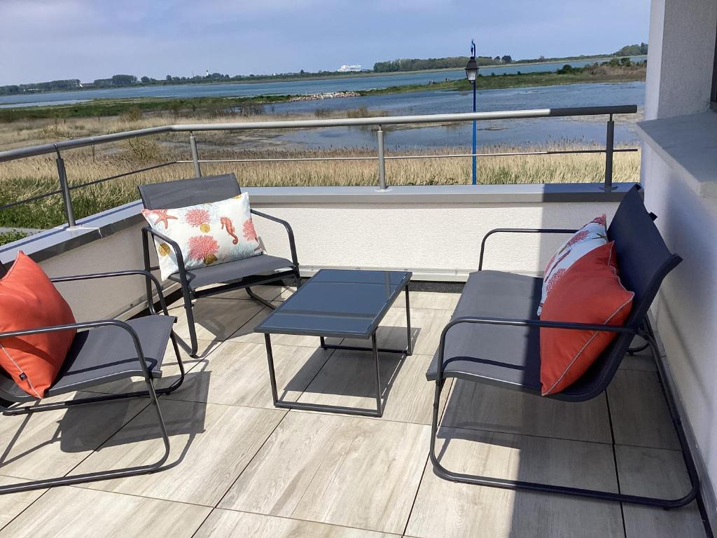 two chairs and a table on a balcony with the ocean at Sallenelles Face à la baie in Sallenelles