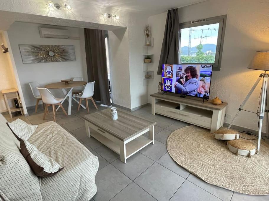un salon avec un canapé et une télévision dans l'établissement T2 lumineux Mer à pied Terrasse Piscine, à Cannes