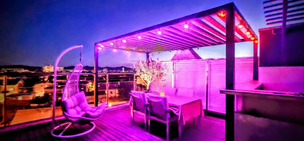 balcone con luci viola, tavolo e sedie di Apartment Zaralux a Zara (Zadar)