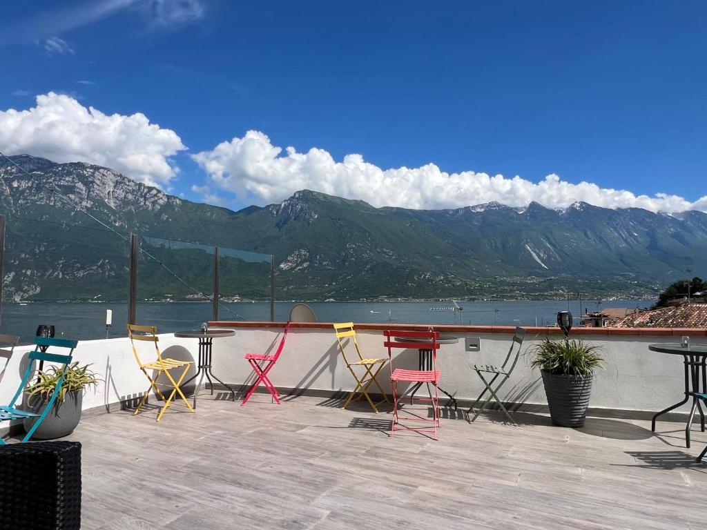 - un ensemble de chaises et de tables sur une terrasse avec des montagnes dans l'établissement Nelson Apartment, à Limone sul Garda