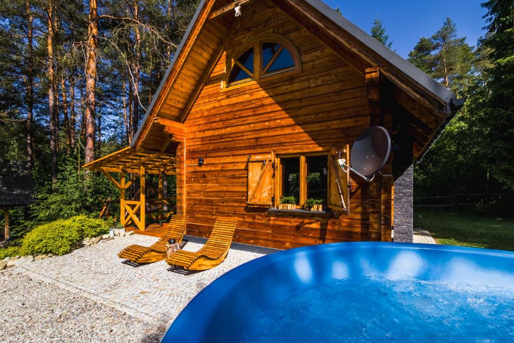 a log cabin with chairs and a swimming pool at Smerekowiec domek w lesie in Smerekowiec