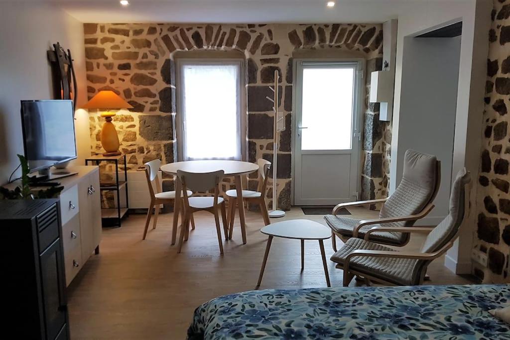 une chambre avec un lit, une table et des chaises dans l'établissement Studio chaleureux 5 mns chaine des Puys, à Saint-Genès-Champanelle