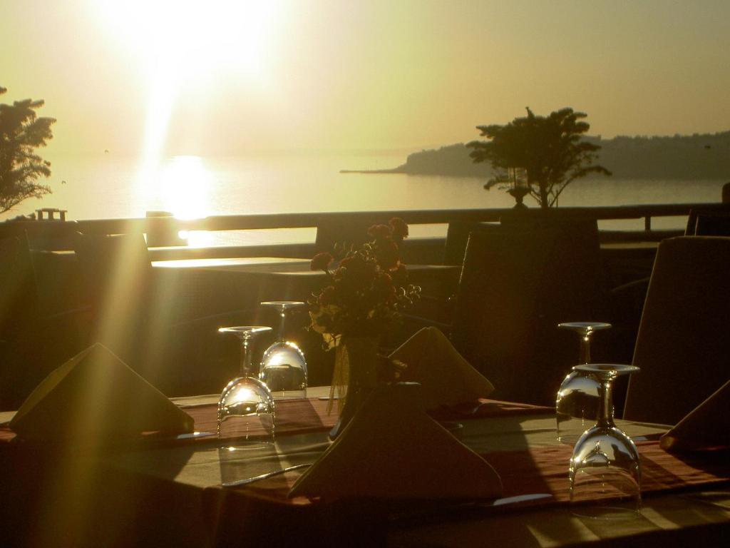 a table with glasses and flowers on it with the sunset at Silivri Park Hotel in Silivri
