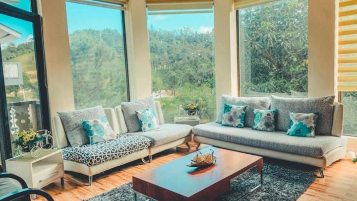 - un salon avec deux canapés et une grande fenêtre dans l'établissement Insta-Worthy Swiss House Staycation Crosswinds Tagaytay, à Tagaytay