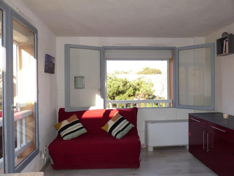 - un salon avec un canapé rouge en face d'une fenêtre dans l'établissement Charmant studio climatisé au milieu du parc naturel, à Marseille
