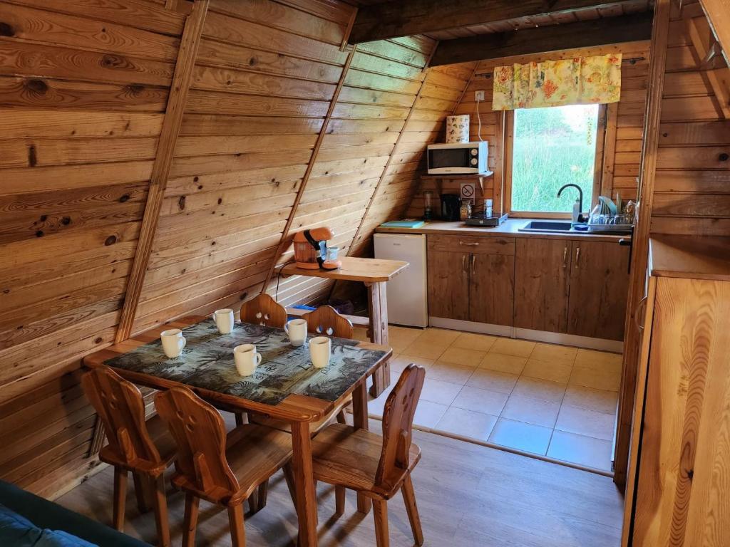 a kitchen with a table and chairs in a cabin at Domki Nad Starą Regą in Mrzeżyno
