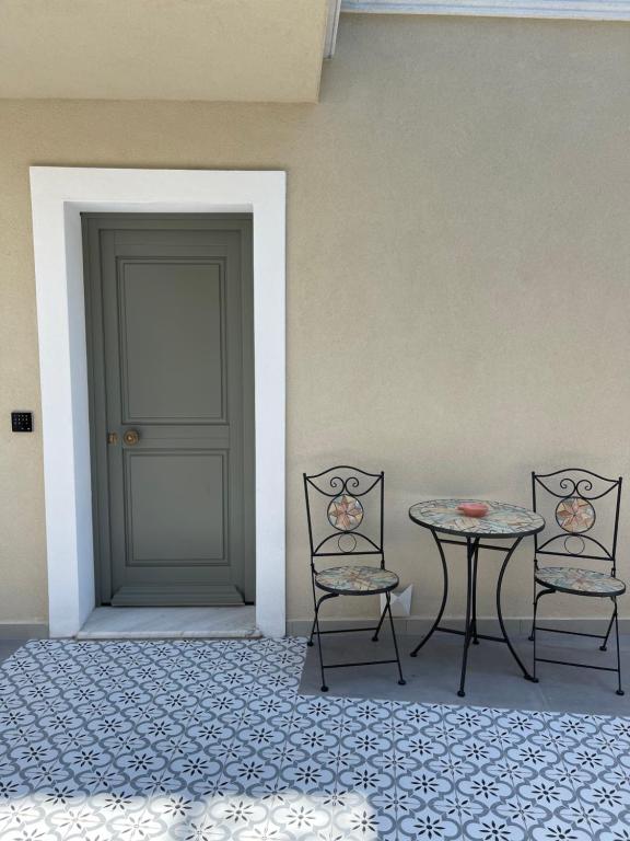 una mesa y dos sillas junto a una puerta en Aesthesis Arxontiko Luxury Rooms, en Mirina