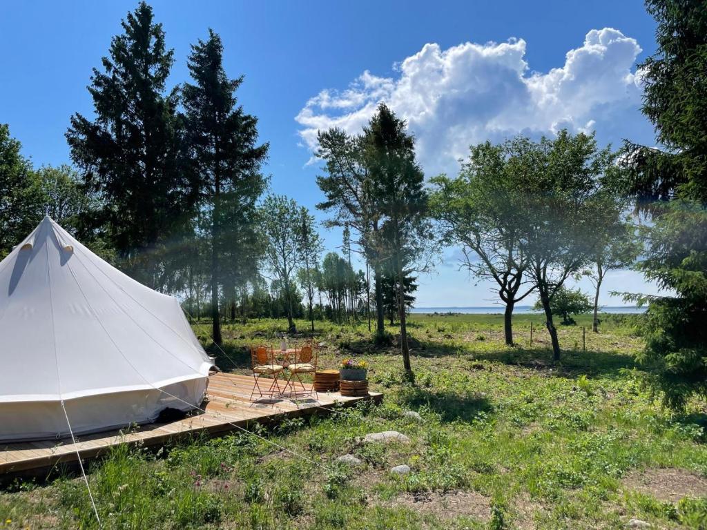 une tente blanche sur une plate-forme en bois dans un champ dans l'établissement Pädaste Aerga Sunset Glamping, à Pädaste