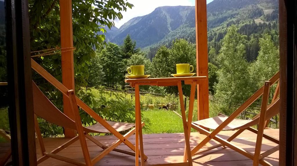 una mesa y sillas en un porche con vistas a las montañas en Cabana Bradut Borsa, en Statjunea Borsa