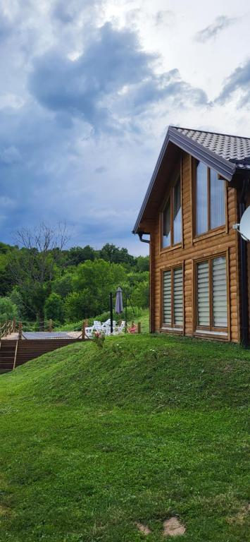 une maison en bois sur une colline herbeuse à côté d'une maison dans l'établissement Vikendica Brvnara Marčetić, à Banja Luka