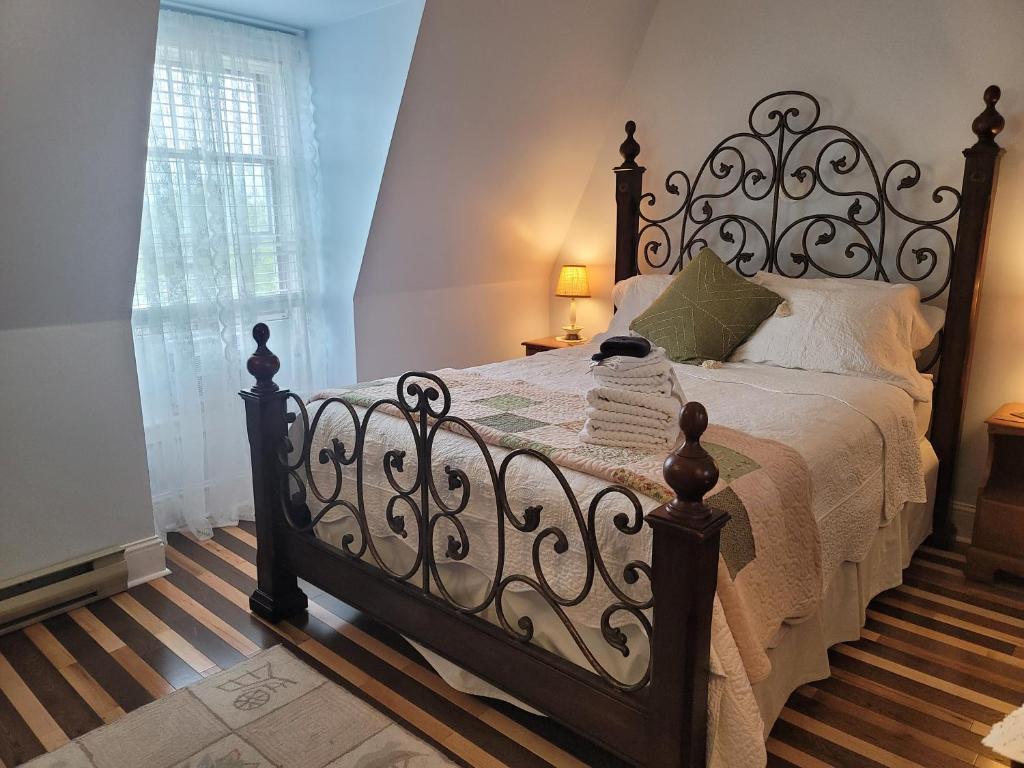 um quarto com uma cama grande e uma cabeceira em ferro forjado em The Scotsman Inn em Pictou