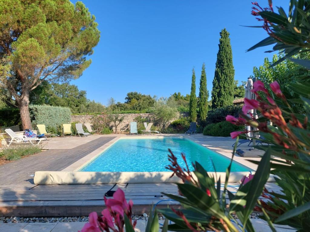 une piscine dans un jardin avec des fleurs violettes dans l'établissement gite de Pierrebrune, à Issirac