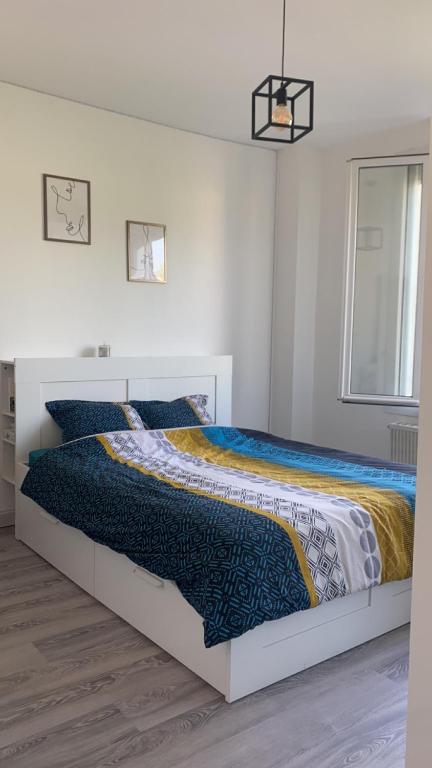 - une chambre blanche avec un lit et une couette colorée dans l'établissement Chambre Allonnes à 10 min du circuit, à Allonnes