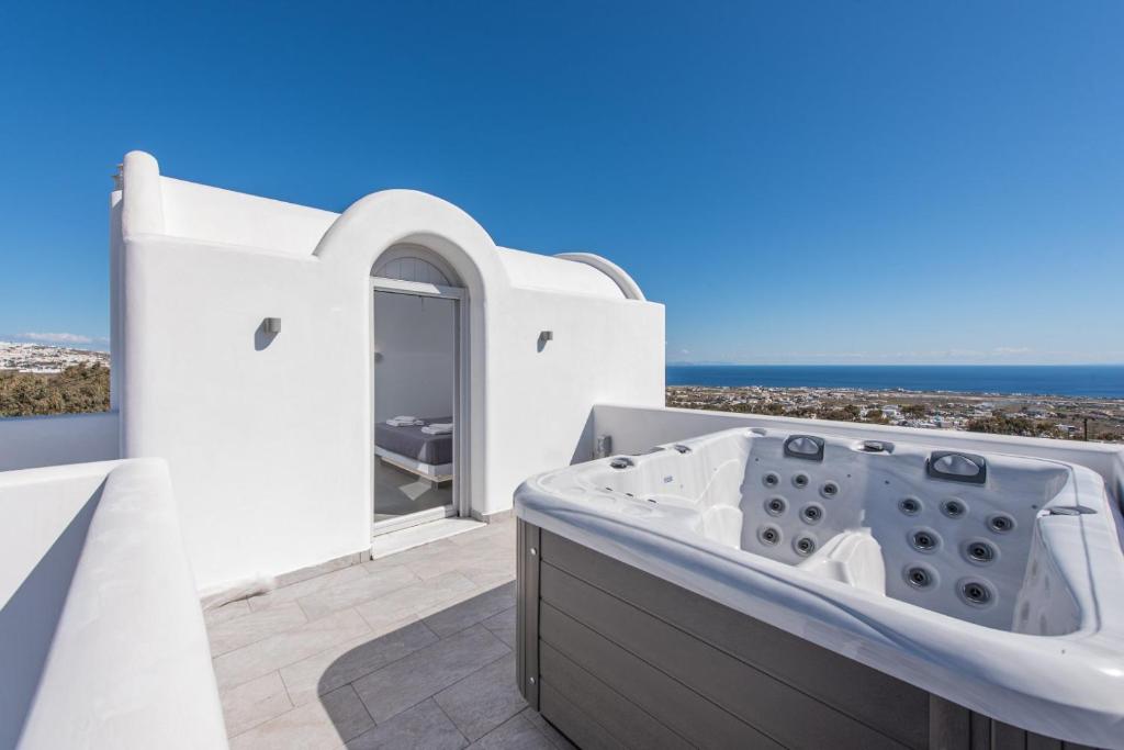 a white bathroom with a tub and a view of the ocean at Golden View Suites with hot tub in Vóthon