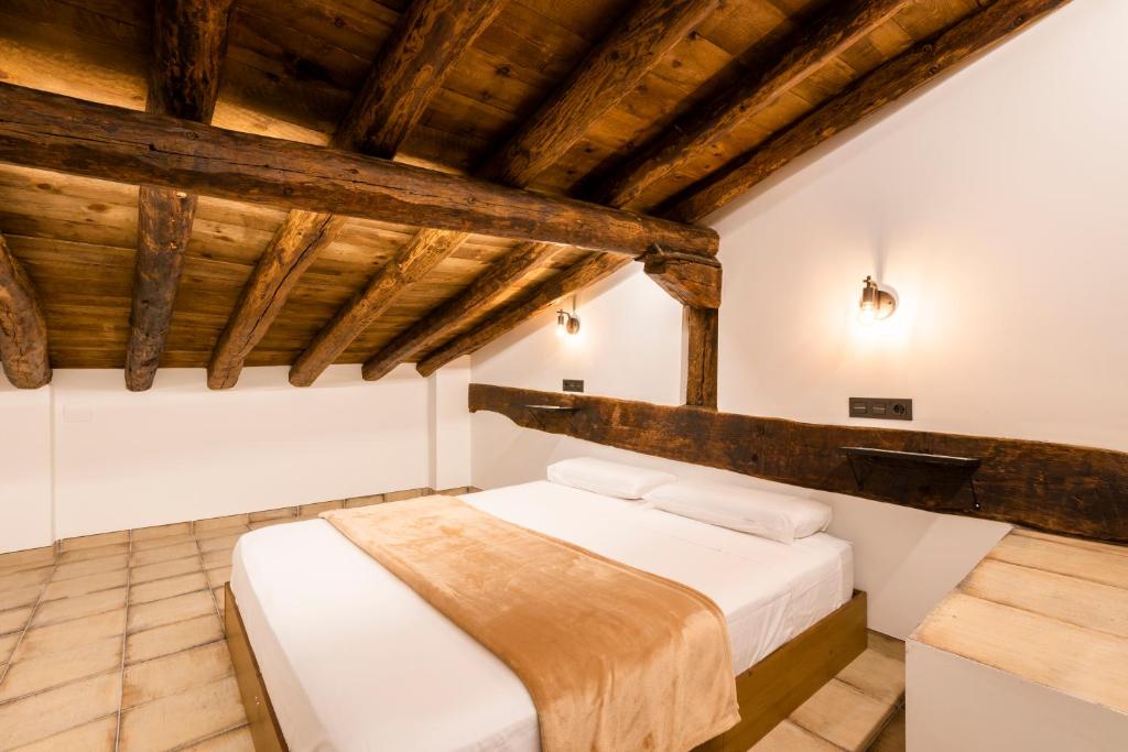 a bed in a room with wooden ceilings at La Botica in Albarracín