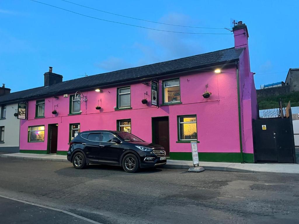 a black car parked in front of a pink building at Danny's Bar Restaurant & accommodation in Broadford