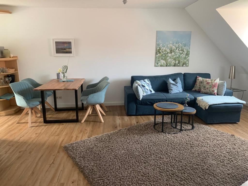 ein Wohnzimmer mit einem blauen Sofa und einem Tisch in der Unterkunft "de hyggelige Loftrum" in Eckernförde