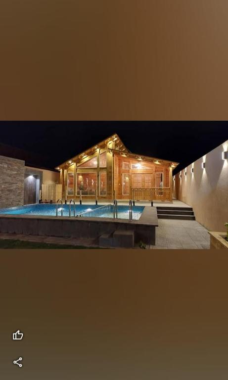 a building with a large pool in front of it at اكواخ السمو الريفيه in Khalij Salman