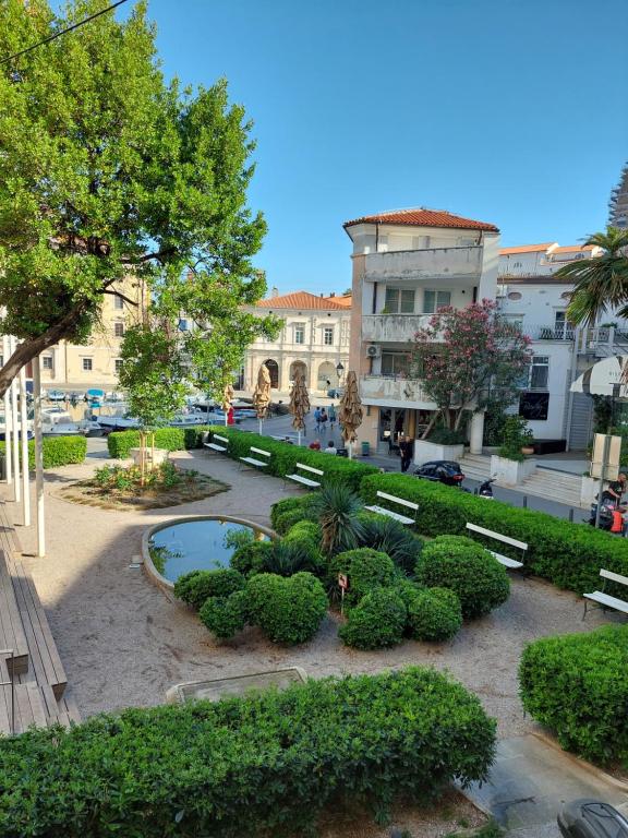 a park with bushes and a pond in front of a building at Nonno Sergio in Piran