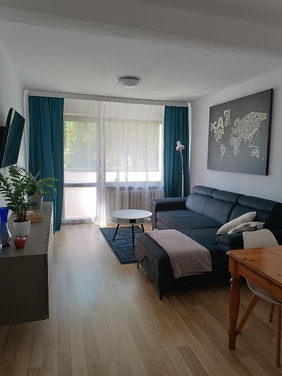 a living room with a blue couch and a table at Apartament Southy in Koszalin