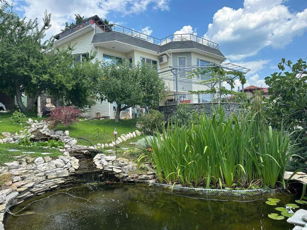 a large house with a pond in front of it at Вила Рак-Апартаменти за гости in Varna City