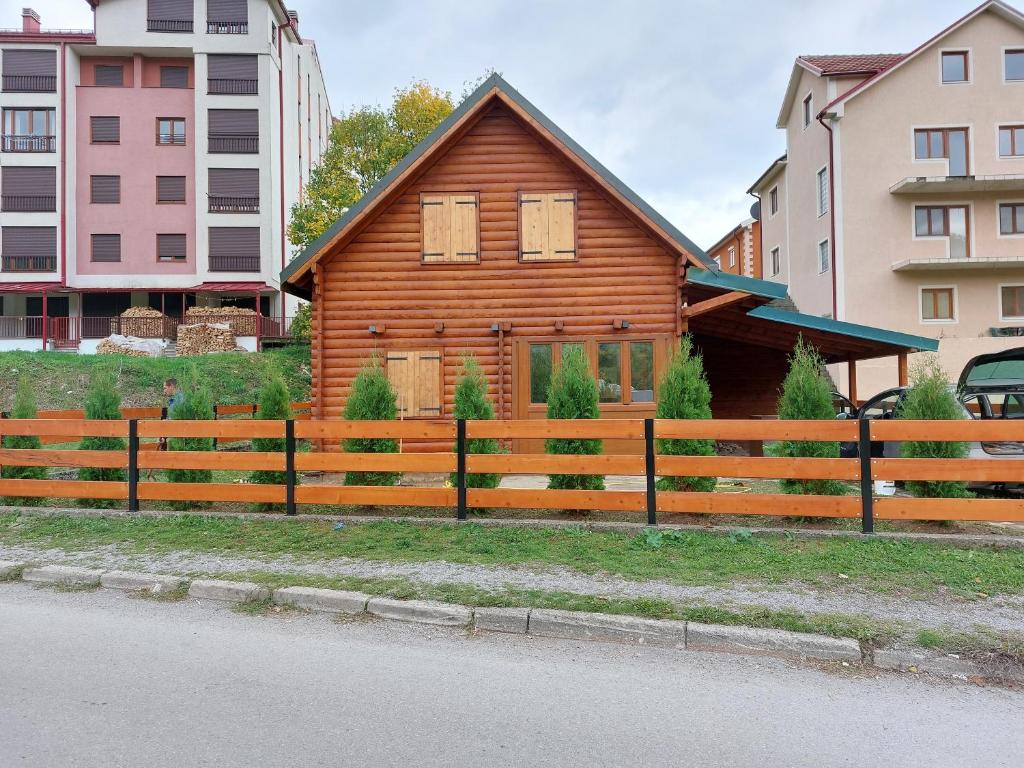 a wooden house with a fence next to some buildings at Zara Chalet in Kolašin