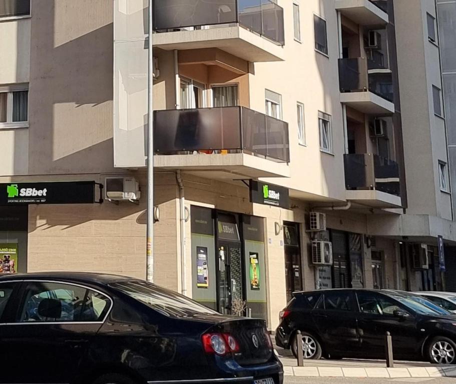 two cars parked on a street in front of a building at Azra apartment City kvart in Podgorica