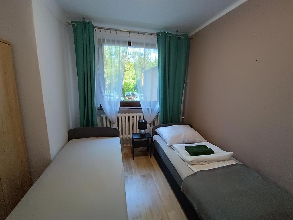 two beds in a room with green curtains and a window at Apartament Southy in Koszalin